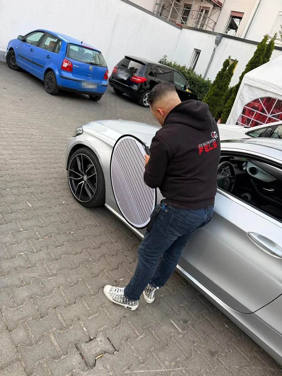 FELZ-Sachverständiger prüft die Fahrzeugseite mit einer Reflektortafel