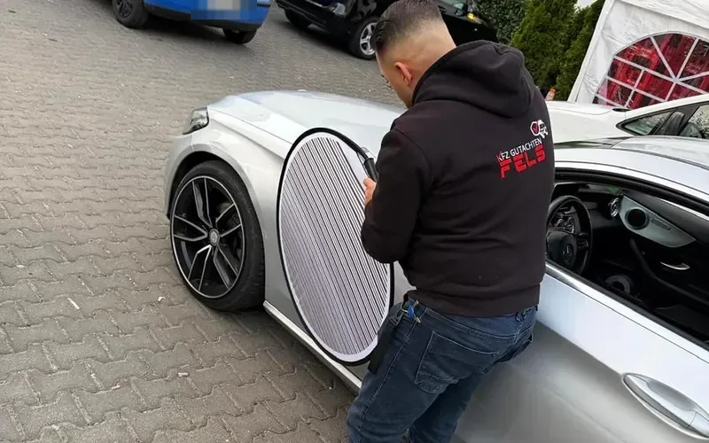 FELZ-Sachverständiger prüft die Fahrzeugseite mit einer Reflektortafel