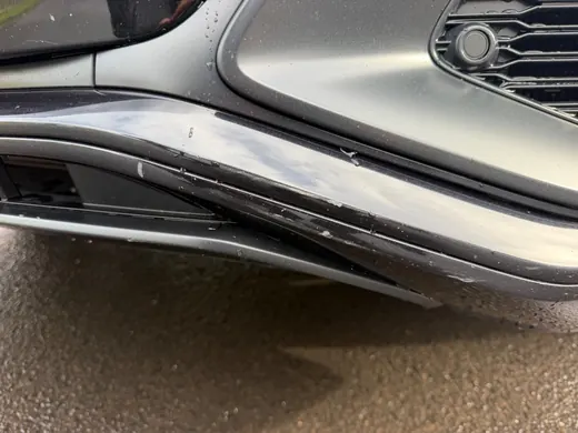 Lackabplatzer an der Zierleiste unter dem seitlichen Lufteinlass eines Audi Q8, daneben der Sensor der Einparkhilfe