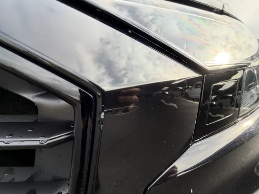 Lackschaden an der Stoßfängerkante neben dem Kühlergrill eines Audi Q8