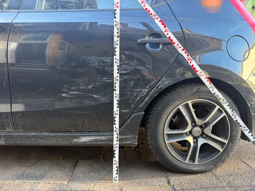 Seite eines schwarzen Hyundai i30 mit Messlatte und Markierungsband zur Dokumentation eines Streifschadens