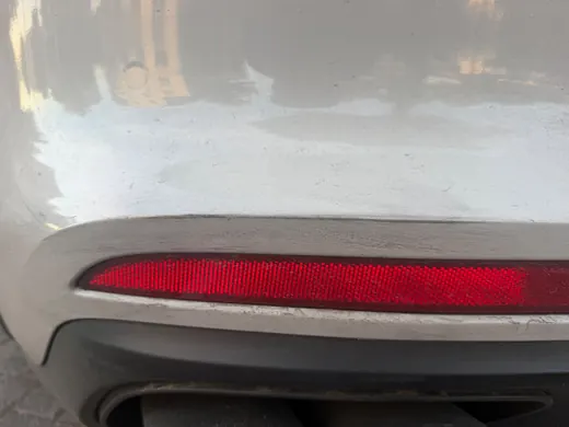 Kratzer an der Stoßfängerverkleidung über dem Rückstrahler eines Porsche Panamera